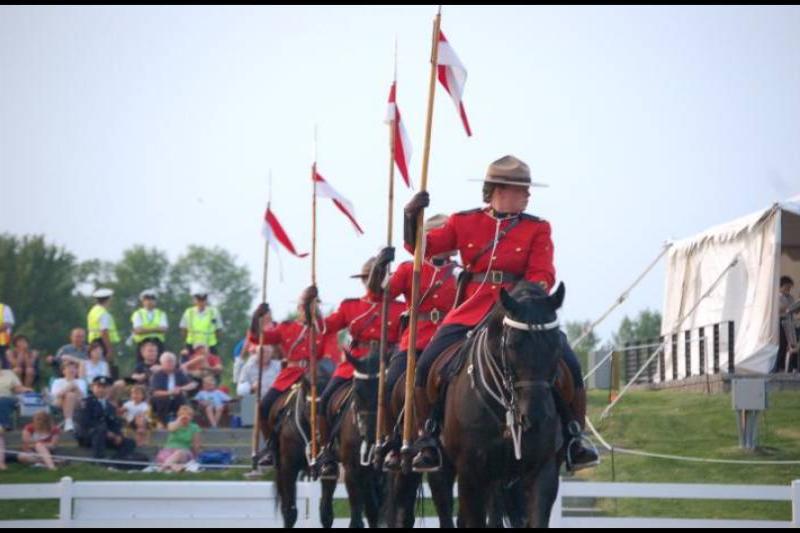 Парад конных рядах RCMP в Канаде: красные мундиры и флаги на фоне зрителей