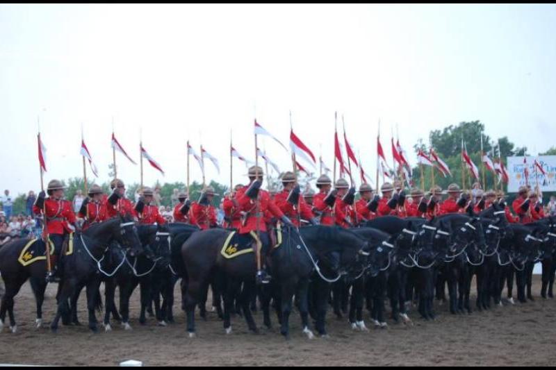 RCMP в красных мундирах и чёрных лошадях на поле в Канаде