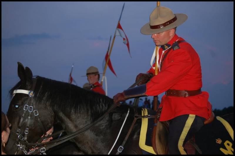 RCMP в красных мундирах на конях у заката в Канаде