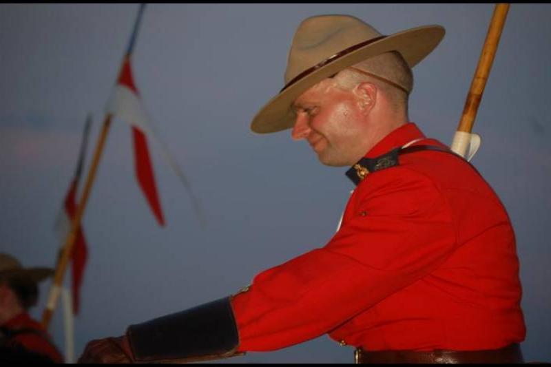 RCMP в красной форме на закате у флага Канады