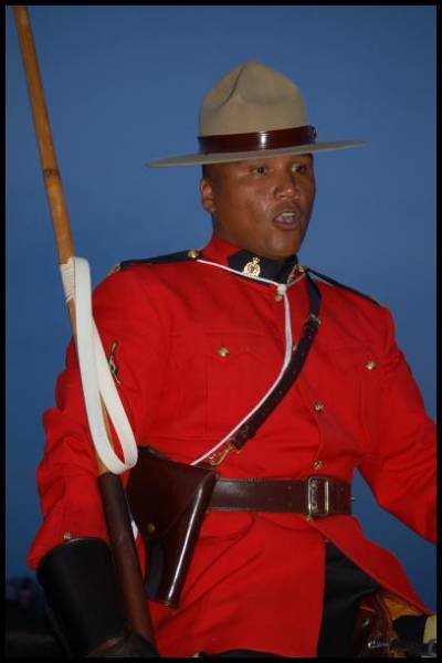 RCMP-полицейский в красной форме с ружьём на фоне заката в Канаде