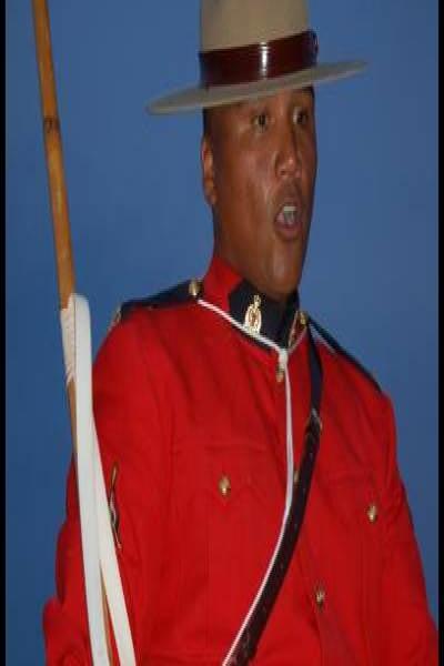 RCMP-полицейский в красной форме с ружьём на фоне заката в Канаде
