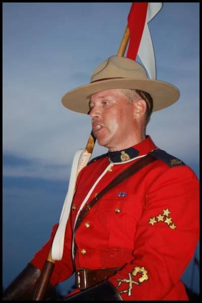 RCMP в красном мундире с флагом на фоне заката в Канаде