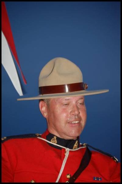 RCMP в форме с шляпой-федорой на фоне флага Канады