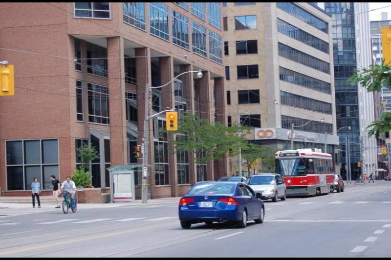 Торонто, 22 июля 2007: красно-белый трамвай на улице с кирпичными зданиями