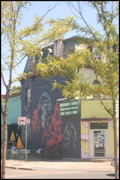 Фасад здания с граффити и вывеской «Crossman's Tavern» в Торонто