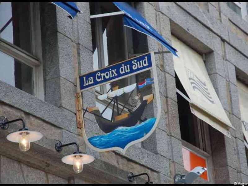 Вывеска «La Croix du Sud» с изображением корабля на фасаде каменного здания