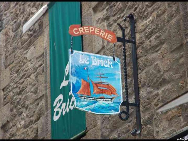 Creperie Le Brick в Сент-Мало: вывеска с парусником на каменной стене