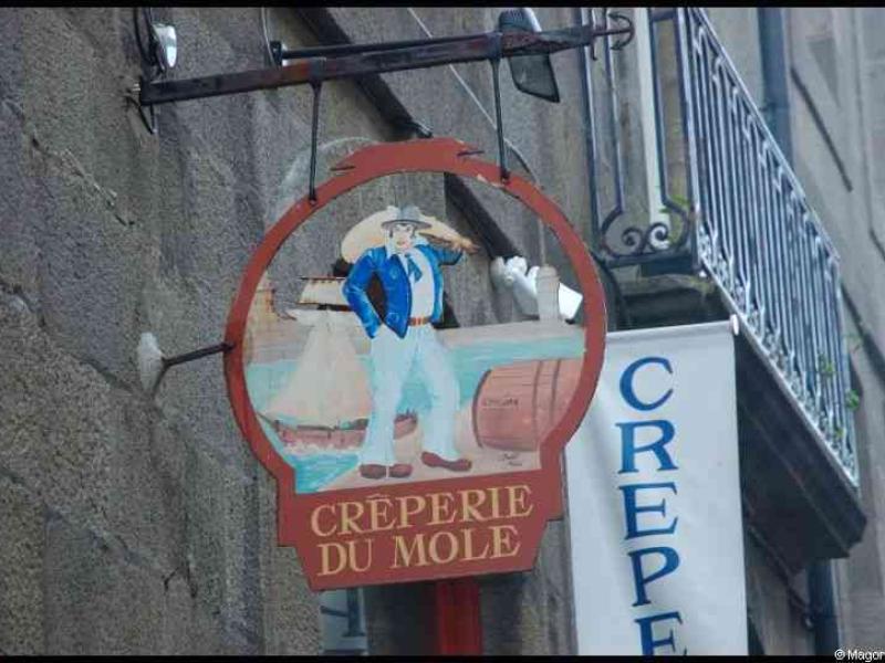 Круглая вывеска «Crêperie du Mole» у старинной стены в Сент-Мало