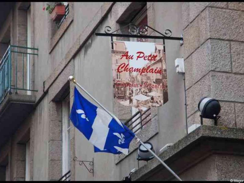 Saint Malo: флаг Квебека и вывеска «Au Petit Champlain» у старинного здания