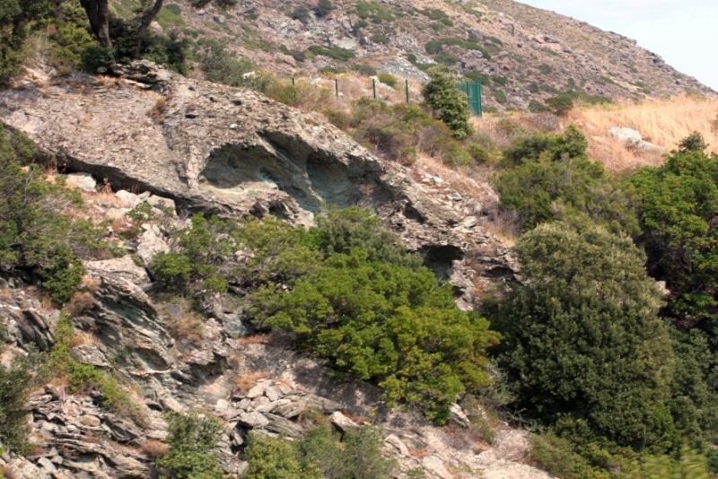 Каменистый склон с пещерой и зелёной растительностью в Корсе