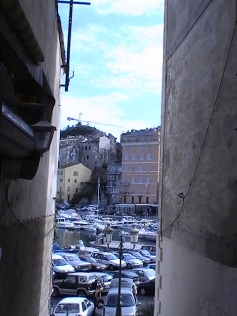Ajaccio, 2008: узкий проход между стенами, за которым — порт и холм с домами