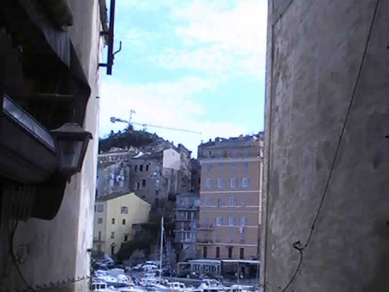 Ajaccio, 2008: узкий проход между стенами, за которым — порт и холм с домами