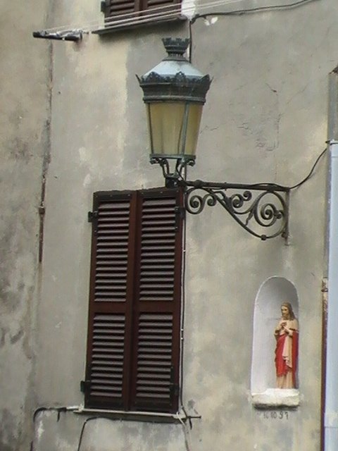 Ajaccio, 2008: фонарь над окном с резной решеткой и нишей со статуей
