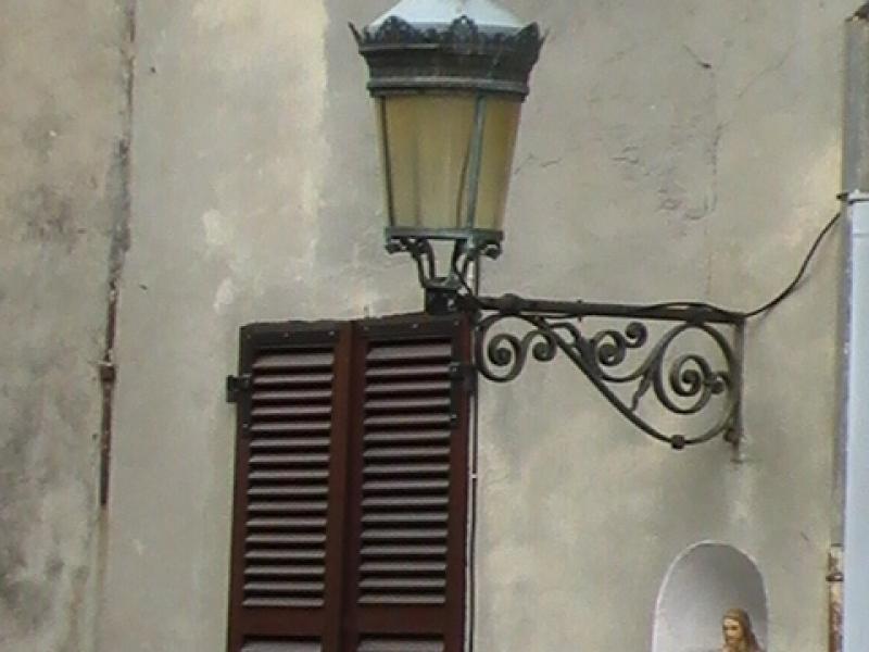 Ajaccio, 2008: фонарь над окном с резной решеткой и нишей со статуей