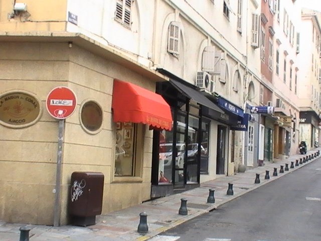 Ajaccio, 2008: улица с красной и чёрной навесами у здания из местного камня