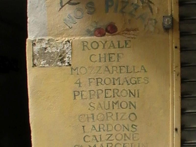 Ajaccio, 2008: вывеска пиццерии с перечнем начинок на желтоватой стене