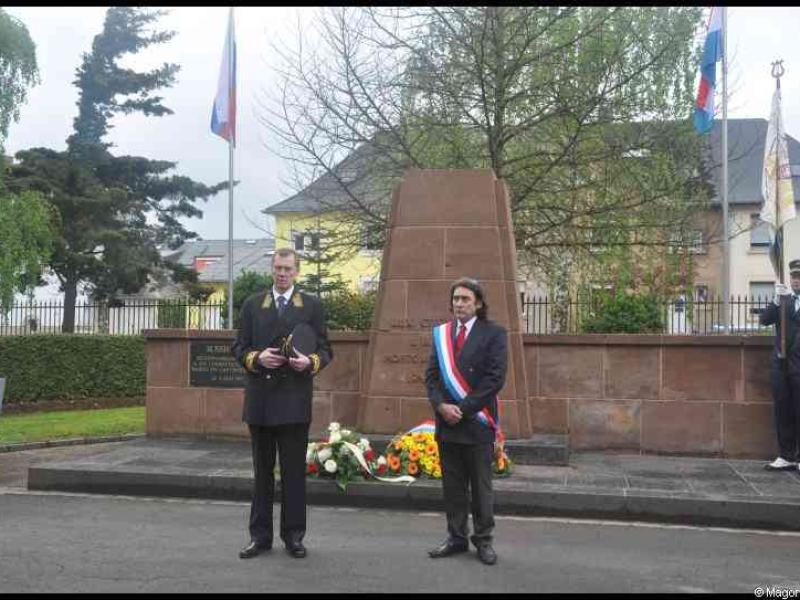 Монумент в Люксембурге, 7 мая 2012: три флага, цветы и официальная церемония