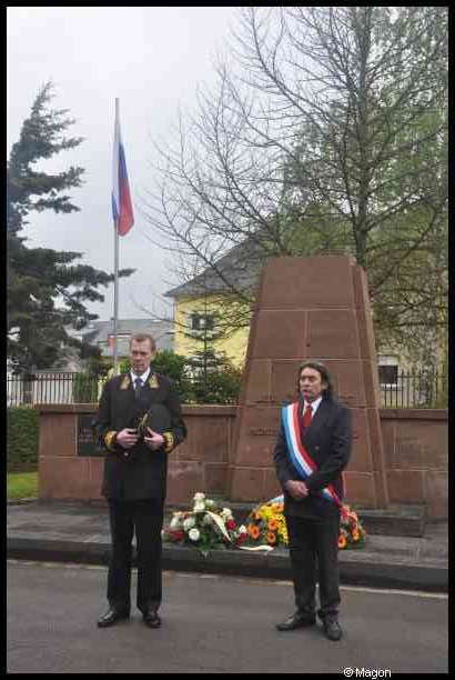 Мемориал в Люксембурге, 7 мая 2012: двое в форменных костюмах у памятника с цветами и флагом