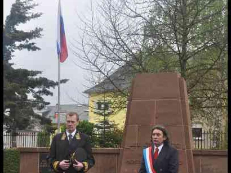 Мемориал в Люксембурге, 7 мая 2012: двое в форменных костюмах у памятника с цветами и флагом
