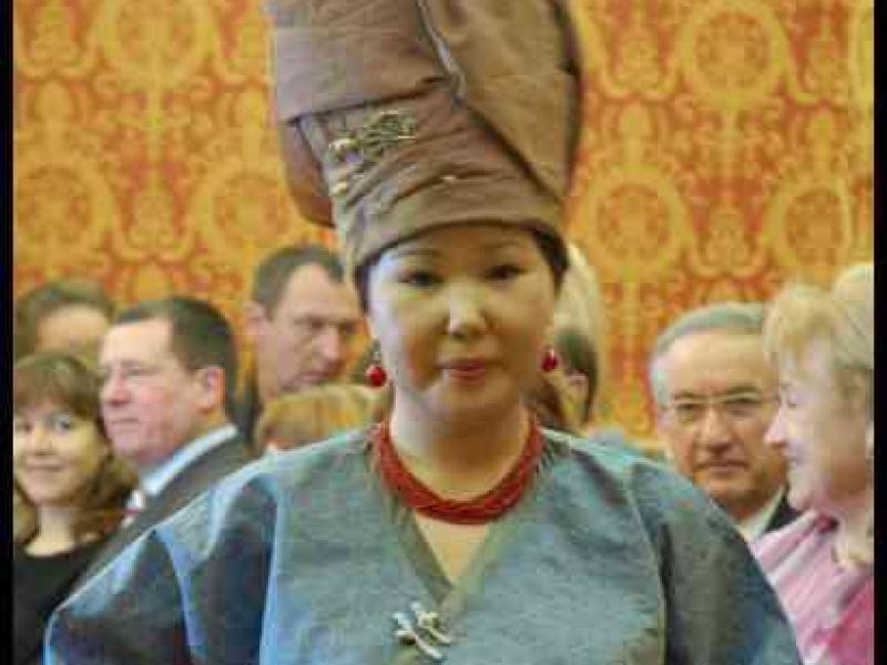 Люксембург, 13 января 2011: женщина в традиционном костюме на фоне золотисто-красного узора стены