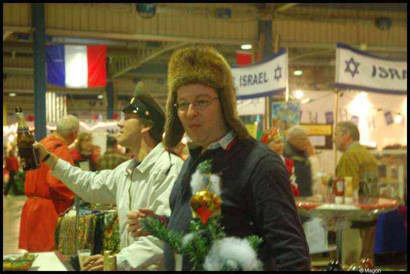 Bazzar в Люксембурге, 2009: мужчина в меховой шапке и маленький елочный декор у столов с флагами Израиля и Франции