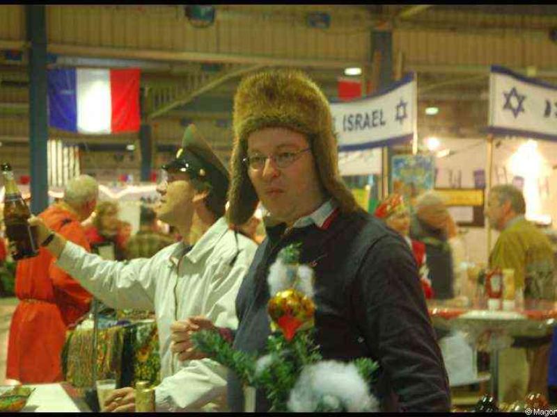 Bazzar в Люксембурге, 2009: мужчина в меховой шапке и маленький елочный декор у столов с флагами Израиля и Франции