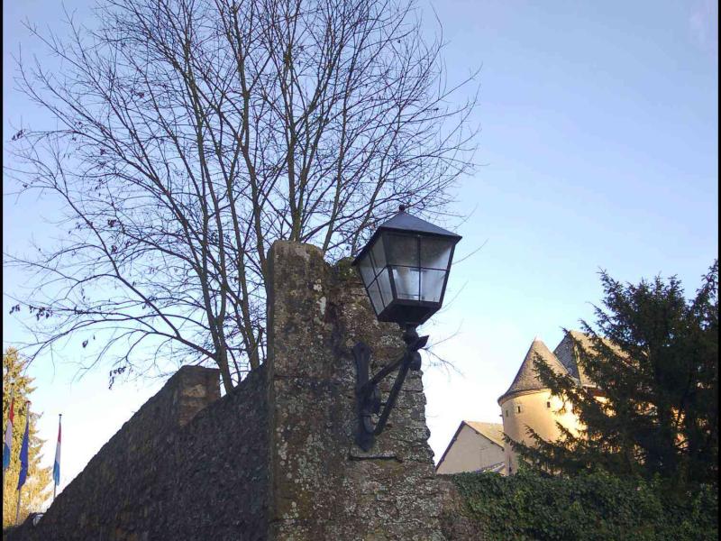 Старинная каменная стена с фонарём в Bourglinster, Люксембург