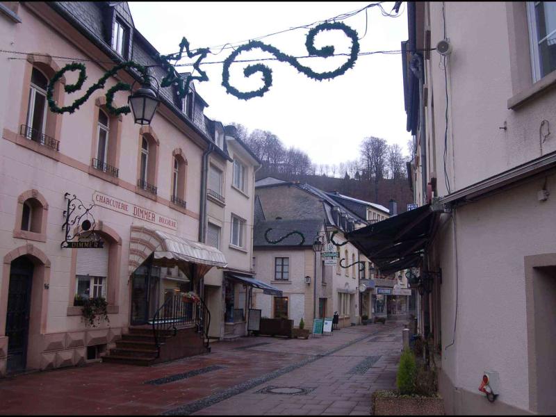 Clervaux, Люксембург: узкая улочка с витринами и зелёными гирляндами