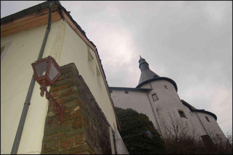 Clervaux, Люксембург: белая башня с конической крышей и старинный фонарь у стены