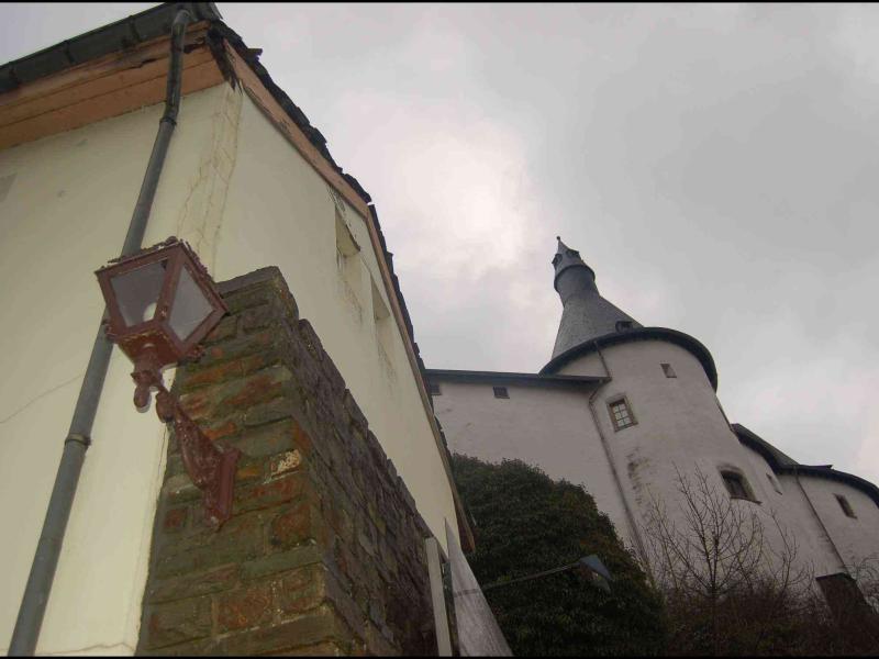Clervaux, Люксембург: белая башня с конической крышей и старинный фонарь у стены