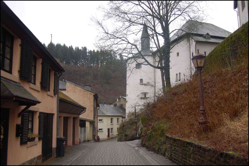 Clervaux: узкая каменная улочка у белой башни с конической крышей