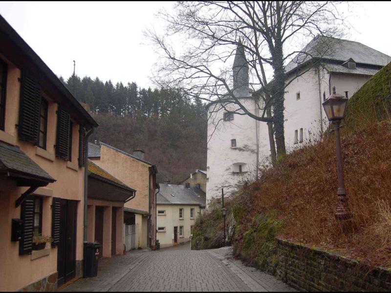 Clervaux: узкая каменная улочка у белой башни с конической крышей