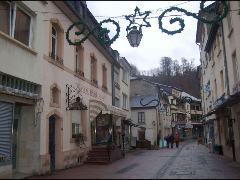Узкая улочка в Clervaux, Люксембург: фонарь и зелёные гирлянды над бутиком Dimmer
