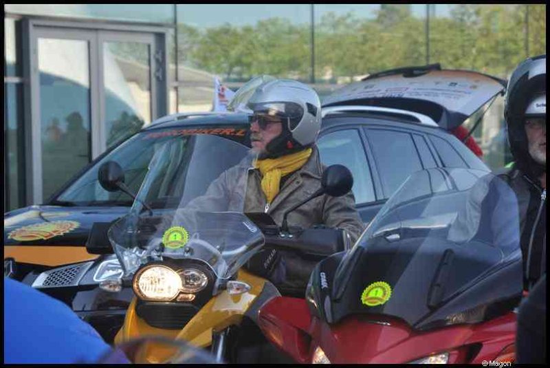 Мотоциклисты в шлемах и шарфах на парковке рядом с автомобилями