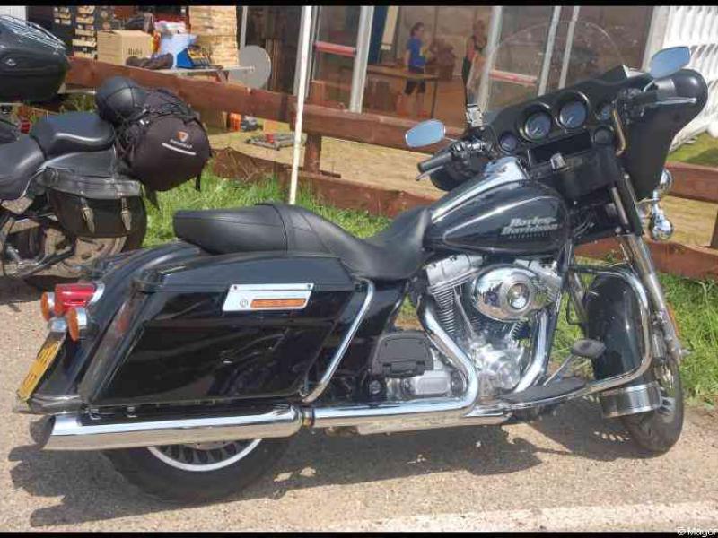 Hog, Люксембург, 2010: чёрный Harley-Davidson с багажниками у деревянного забора