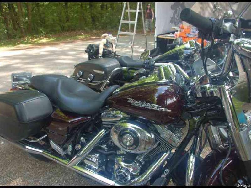 Темно-бордовый мотоцикл Harley-Davidson с хромированными деталями и багажниками на выставке