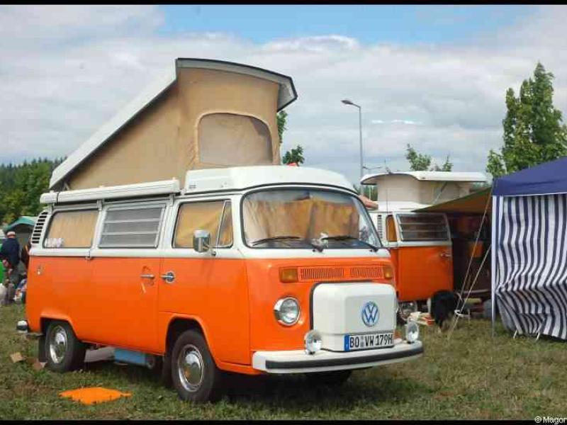 Оранжевый фургон Volkswagen с поднимаемым кузовом и бежевой крышей на выставке