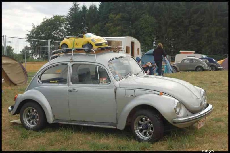 Серебристый Volkswagen Beetle с детской машинкой на крыше на выставке автомобилей