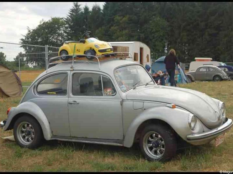 Серебристый Volkswagen Beetle с детской машинкой на крыше на выставке автомобилей
