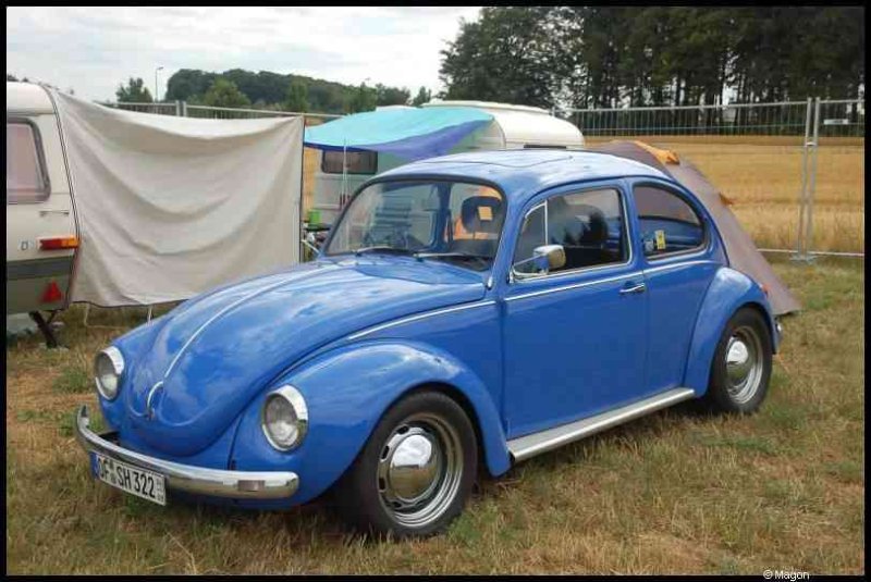 Luxbug 2010: синий Volkswagen Beetle на поле с карavans и палатками