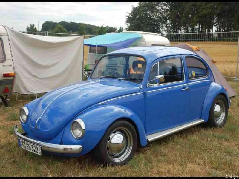 Luxbug 2010: синий Volkswagen Beetle на поле с карavans и палатками
