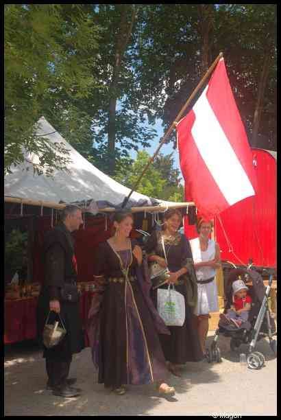 Medieval Festival Useldange, Люксембург: женщины в средневековых нарядах у красно-белого флага