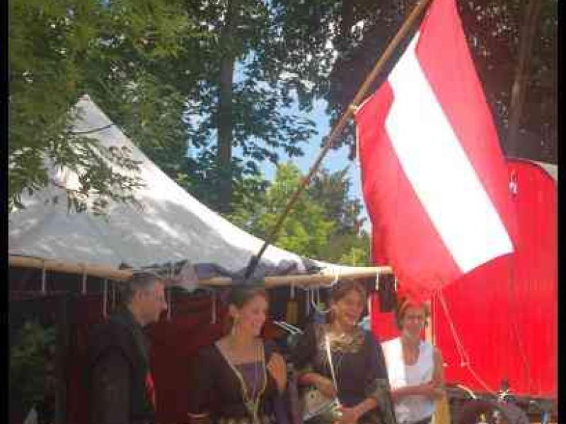 Medieval Festival Useldange, Люксембург: женщины в средневековых нарядах у красно-белого флага