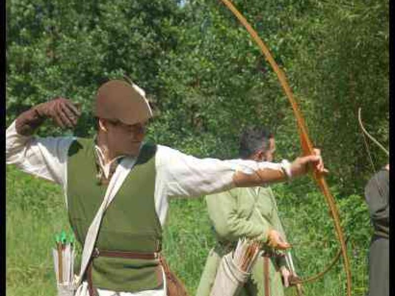 Medieval Festival Useldange, Люксембург: лучник в зелёном жилете тянет тетиву лука