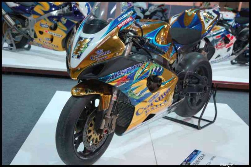 Спортивный мотоцикл Suzuki с золотисто-синей ливреей на выставке
