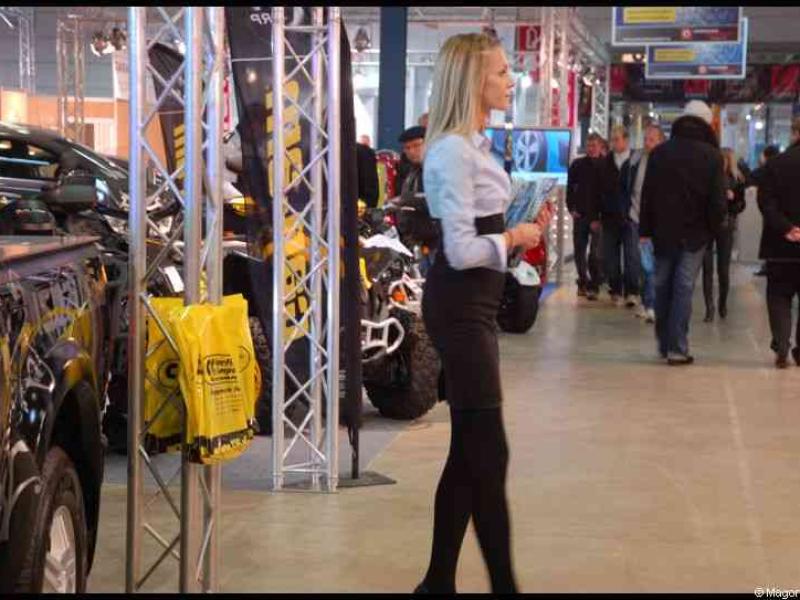 Женщина в деловом костюме на выставке автомобилей и мототехники