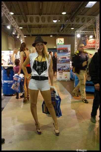 Motorshow 2010 в Люксембурге: женщина в шляпе и белом костюме у стойки с маслом