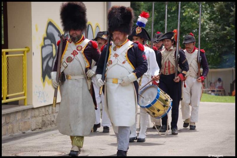 Napoleonic Bivouac в Люксембурге: солдаты в шляпах-шапках и белых фартуках проходят мимо желтого забора