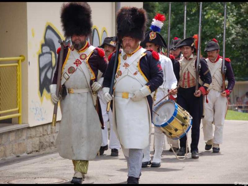 Napoleonic Bivouac в Люксембурге: солдаты в шляпах-шапках и белых фартуках проходят мимо желтого забора